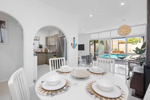 a dining room and kitchen with a white table and chairs at Tropical Zen Stylish Beach-Inspired Home w Pool in Perth