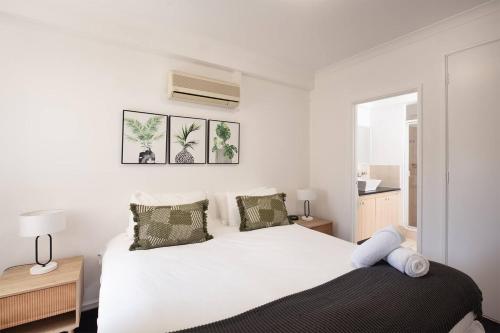 a white bedroom with a bed and two lamps at Spacious 2 Bedroom Pool & Gym PerthCBD,Optus,WACA in Perth