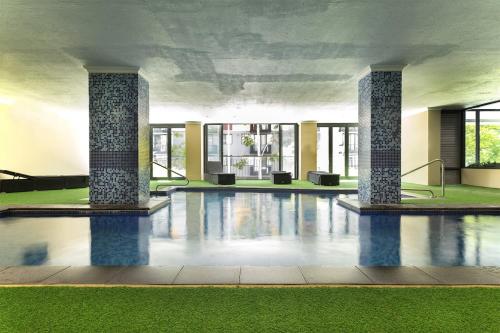 a swimming pool with pillars in a building at Spacious 2 Bedroom Pool & Gym PerthCBD,Optus,WACA in Perth