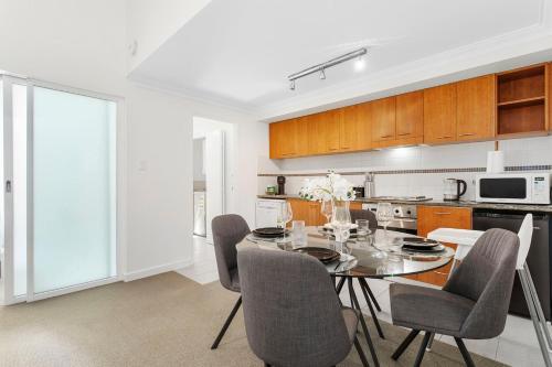 a kitchen with a dining room table and chairs at The CBD Gateway Modern 1BR Suite near UWA & Park in Perth
