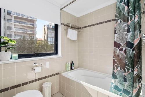 a bathroom with a tub and a window at The CBD Gateway Modern 1BR Suite near UWA & Park in Perth