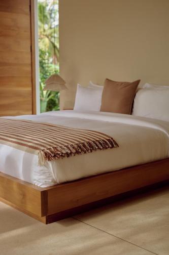 a large bed with a wooden frame in a bedroom at Sola - Boutique Hotel in Ahangama