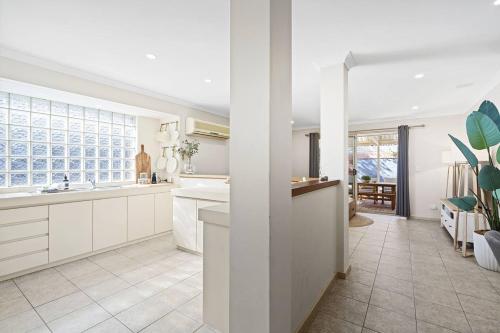 a kitchen with white cabinets and a large window at Rivervale Family Retreat Quiet 3BR Home Near Swan in Perth