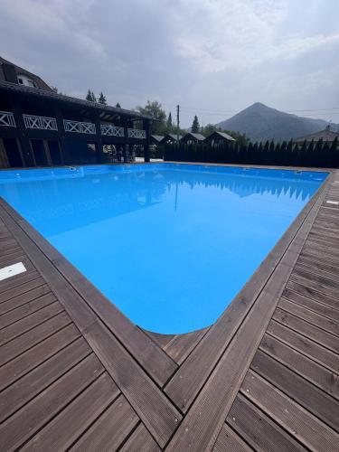 a large blue swimming pool with a wooden deck at Raffaello in Rostoki