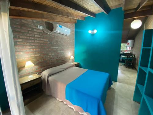 a bedroom with a blue bed and a brick wall at Cabañas Burung Hantu in Merlo