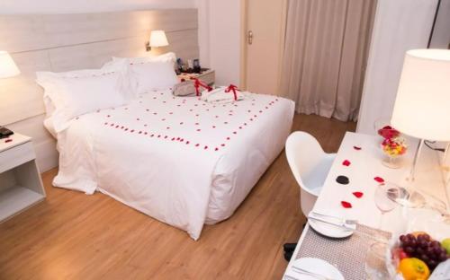 a bedroom with a white bed with red bows on it at Camaçari Plaza Hotel in Camaçari