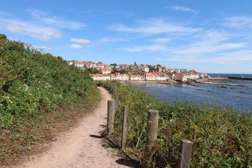 a dirt road next to a body of water with houses at Hayloft in Pittenweem