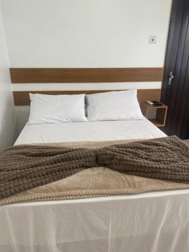 a bed with a brown blanket and white pillows at Hotel LENA in São Luiz Gonzaga