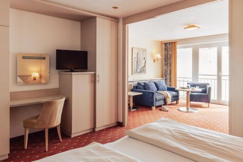 a hotel room with a bed and a living room at Hotel Römerhof Superior in Obertauern