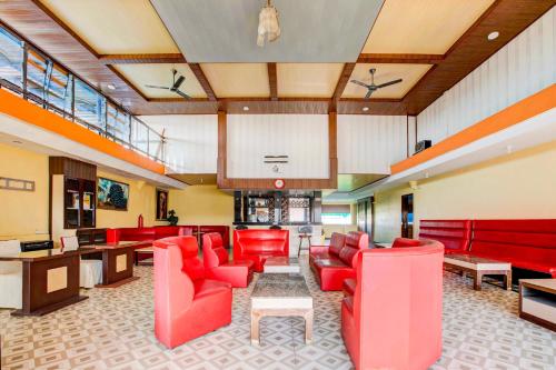 a waiting room with red chairs and tables at Dancenter S Hotel in Tanjunguma