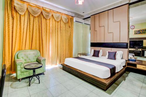 a bedroom with a large bed and a chair at Dancenter S Hotel in Tanjunguma