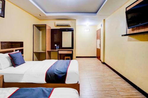 a hotel room with two beds and a flat screen tv at Dancenter S Hotel in Tanjunguma