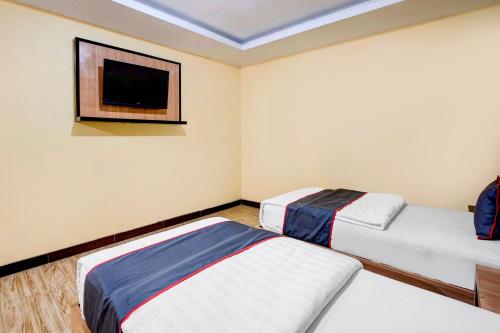 two beds in a room with a tv on the wall at Dancenter S Hotel in Tanjunguma