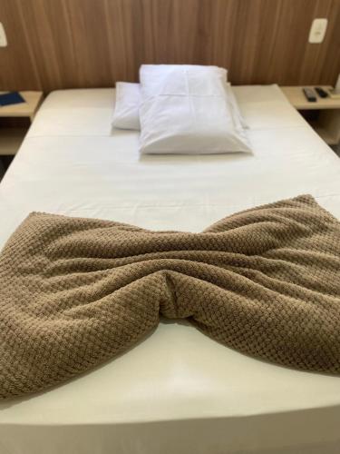 a bed with a brown blanket on top of it at Hotel LENA in São Luiz Gonzaga