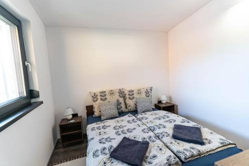 a white bedroom with a bed and a window at Tan'n'baum jacuzzi house Balatonfenyves in Balatonfenyves