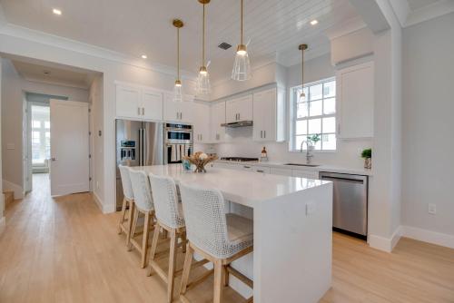 a kitchen with white cabinets and a large island with bar chairs at Sea Glass Cove by SoFLA Vacations in Marathon