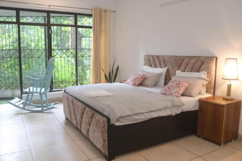a bedroom with a bed with a chair and a window at The Jungle Retreat by Jabula Getaways in Dehradun