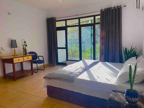 a bedroom with a bed and a desk and a window at The Jungle Retreat by Jabula Getaways in Dehradun