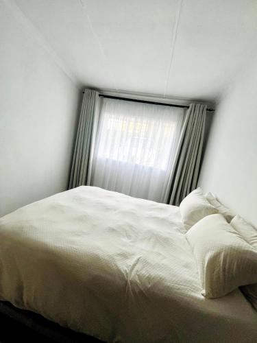 a white bed in a bedroom with a window at Central Maseru - 2 Bedroom Apartment in Maseru