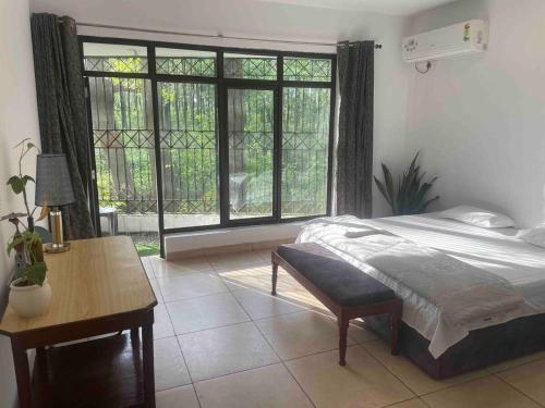 a bedroom with a bed and a table and a window at The Jungle Retreat by Jabula Getaways in Dehradun