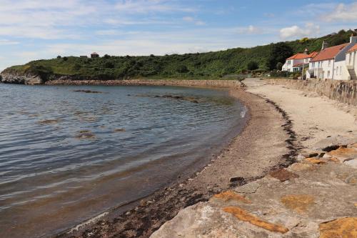 a sandy beach with houses and the water at Maimies Harbourview in Anstruther