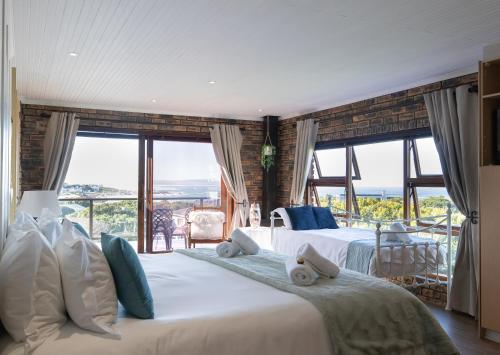 1 dormitorio con 2 camas y ventanas grandes en White Shark Guest House, en Gansbaai