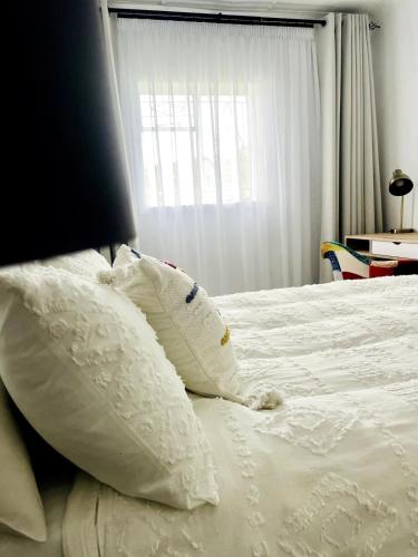 a bed with white pillows on it with a window at Central Maseru - 2 Bedroom Apartment in Maseru