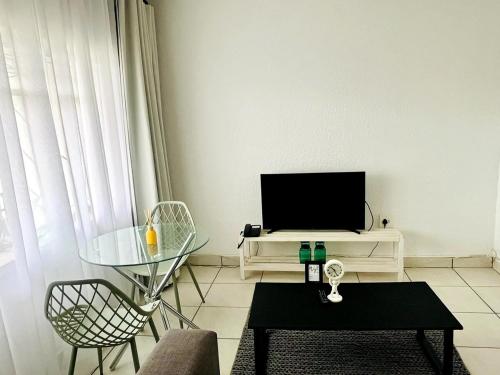 a living room with a table and a tv at Central Maseru - 2 Bedroom Apartment in Maseru