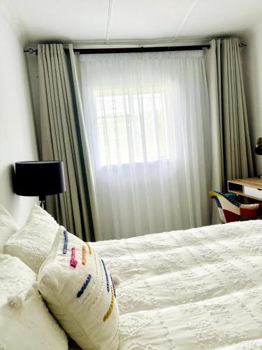 a bed with a pillow on it with a window at Central Maseru - 2 Bedroom Apartment in Maseru