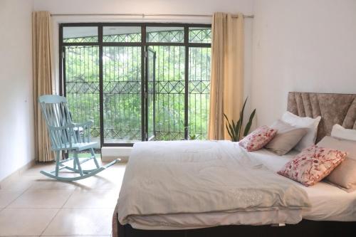a bedroom with a bed and a chair and a window at The Jungle Retreat by Jabula Getaways in Dehradun