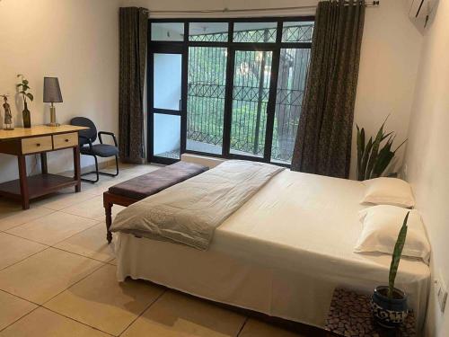 a bedroom with a bed and a desk and a window at The Jungle Retreat by Jabula Getaways in Dehradun