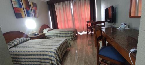 a hotel room with two beds and a table and a television at Hotel Emperador in Valencia