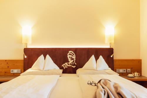 two beds in a hotel room with a picture on the headboard at Hotel Römerhof Superior in Obertauern