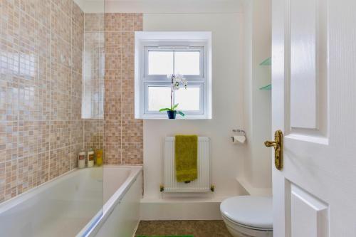 a bathroom with a tub and a toilet and a window at Wimbledon 3 Bed - Free Van Parking - Sleeps 7 - Contractors in Mitcham
