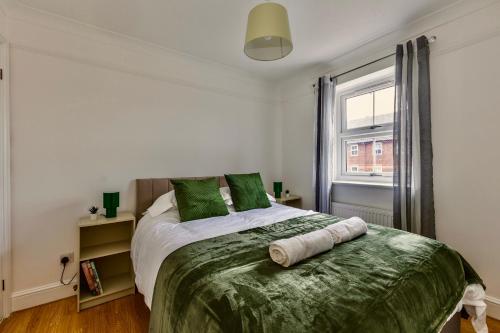 a bedroom with a bed with green pillows and a window at Wimbledon 3 Bed - Free Van Parking - Sleeps 7 - Contractors in Mitcham