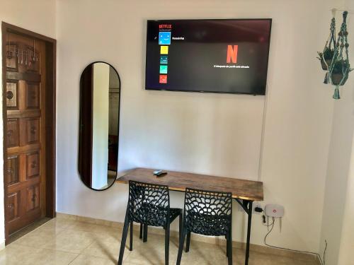 a table with two chairs and a mirror on a wall at Explorer Tours Ilha Grande - Apartamentos no Centro da Vila do Abraão in Abraão
