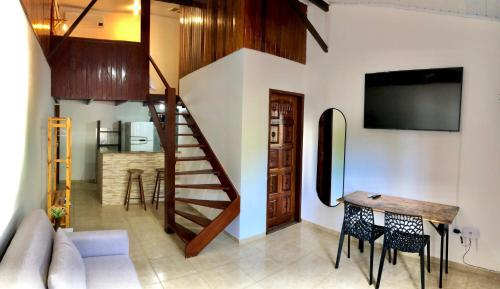 a living room with a staircase and a table and chairs at Explorer Tours Ilha Grande - Apartamentos no Centro da Vila do Abraão in Abraão