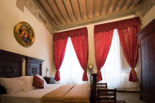 a bedroom with a bed with red curtains at All'ombra della Torre only Rooms in Siena