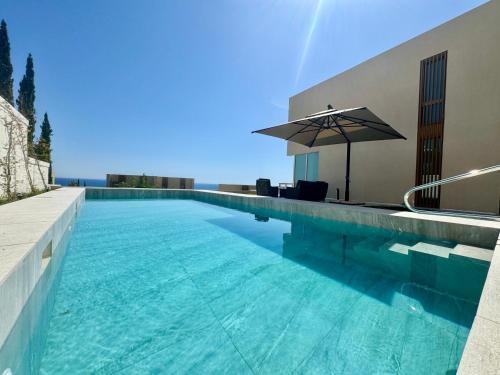 a swimming pool with an umbrella next to a building at Elite Vila with Pool, Green Coast in Palasë