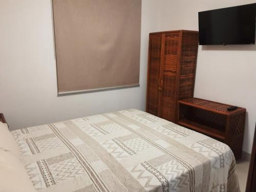 a bedroom with a bed and a flat screen tv at Chalé Pé na Areia e Piscina Privativa em Barra do Jacuípe in Camaçari