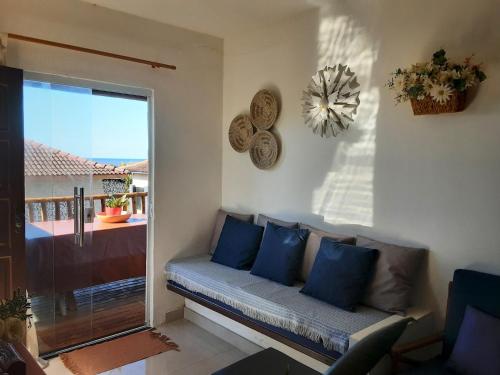 a living room with a couch and a large window at Chalé Pé na Areia e Piscina Privativa em Barra do Jacuípe in Camaçari