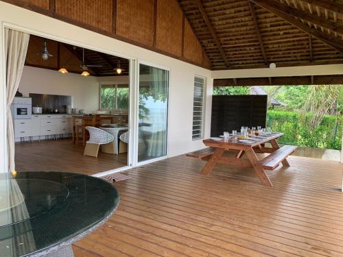 a patio with a table and a dining room and kitchen at Happy T Beach House in Haapiti