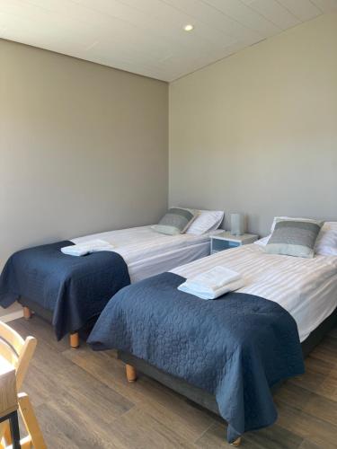 a room with two beds with blue covers and a chair at Strönd Guesthouse in Birkimelur 