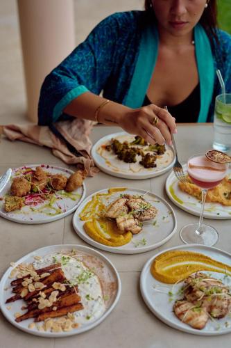a woman sitting at a table with plates of food at Sola - Boutique Hotel in Ahangama