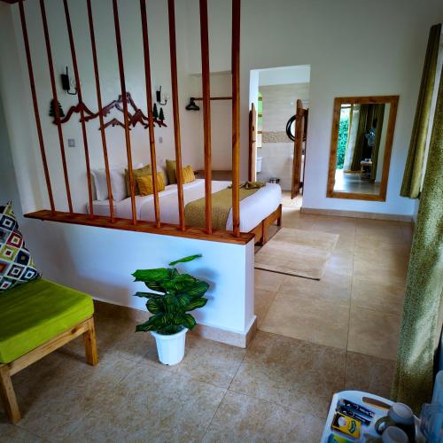 a bedroom with a bed and a plant in a room at Paradise Farm Cottages Mbui Nyeri in Ihua