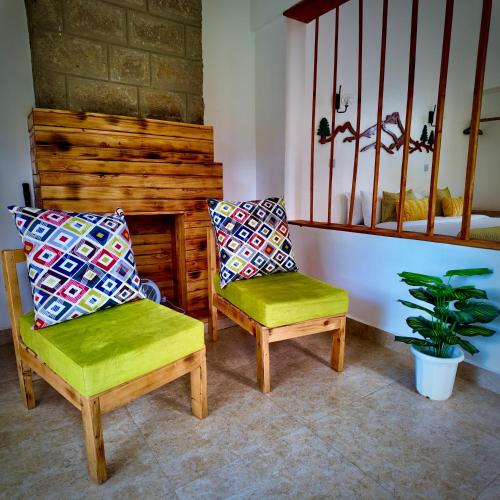 two chairs with colorful pillows sitting in a room at Paradise Farm Cottages Mbui Nyeri in Ihua