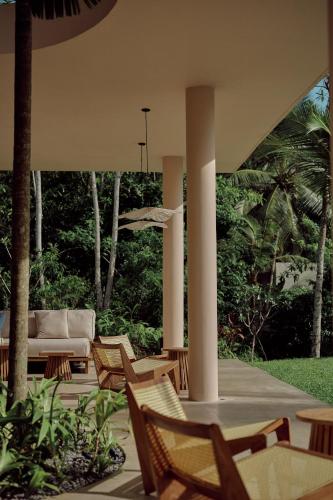 a patio with a couch and chairs and trees at Sola - Boutique Hotel in Ahangama