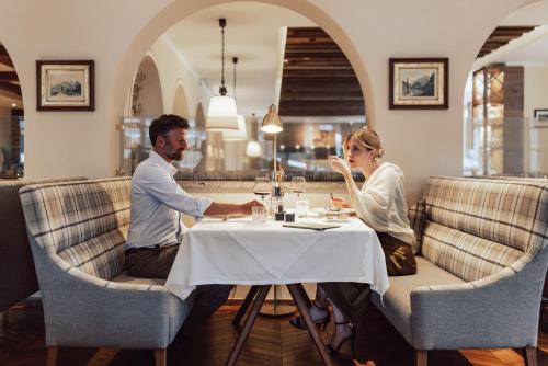 a man and woman sitting at a table in a restaurant at Hotel Römerhof Superior in Obertauern