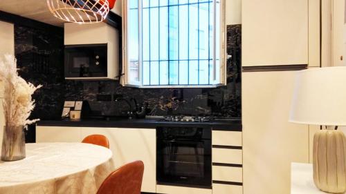 a kitchen with white cabinets and a table and a window at QuickHome La Torretta in Asti