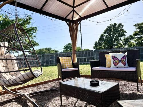 a patio with chairs and a swing and a table at Kings, 75" TV & Backyard Fun - NearWesley in The Dell
